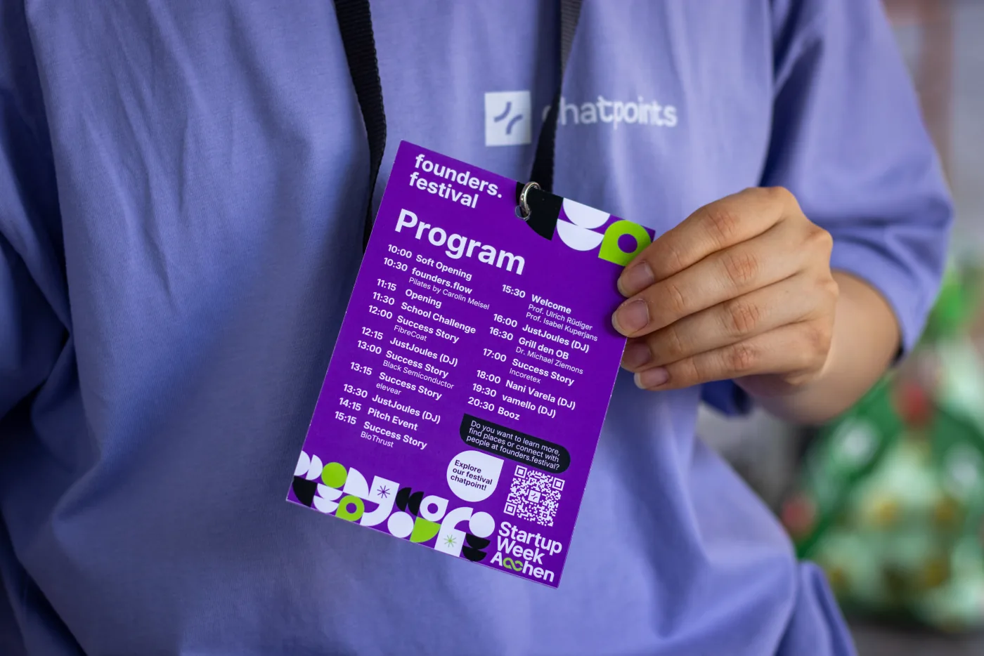 Ein chatpoints-Teammitglied hält die founders.festival-Programmkarte mit integriertem QR-Code