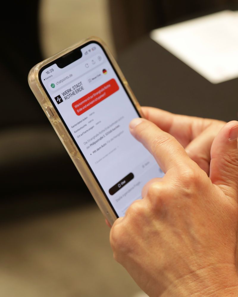 Hände bedienen den digitalen WERK.STADT ROTHE ERDE Guide auf einem Smartphone